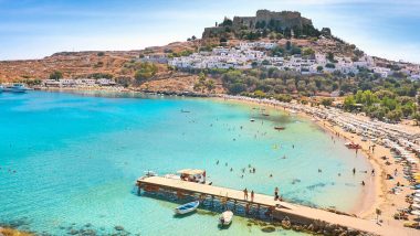 La vivace spiaggia della baia di St Paul nell'Isola Rodi, nella foto le acque turchesi e vista sull'antica acropoli, sull'isola di Rodi in Grecia.