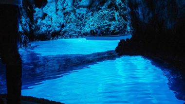 Isola di Bisevo la Grotta Azzurra Baia Balum, illuminata da una straordinaria luce blu naturale che riflette sul mare, creando un'atmosfera magica con una barca che galleggia tranquillamente, circondata da antiche rocce calcaree.