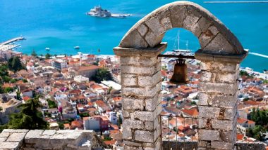 Vista dal Campanile di Poros e la città sottostante, con i suoi tetti in terracotta e le strutture bianche intonacate, si estende fino al porto, dove le barche a vela sono ancorate nelle acque blu.